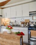 A kitchen with butcher block island and white cabinets.