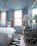 Light blue bedroom with red and white curtains and a mirrored dresser