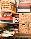 Clothing, shoes, and other items in bins, baskets, and on shelves in closet.