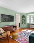 Mint green TV room with green velvet couch and dark wood furniture