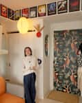 Cozy living space featuring a woman in a cream sweater, orange couch, patterned door, and framed art above.