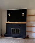 Black painted brick fireplace in living room before renovation.