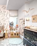Cozy nursery with floral wallpaper, a wooden crib, plush toys, and a changing table, featuring soft pastel colors.