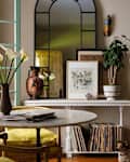 A cozy living space featuring a round marble table, yellow cushions, a vase of calla lilies, and a dog.