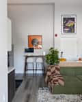 Cozy living space featuring a green sectional sofa with a brown patterned throw, a small dining area, and modern decor.