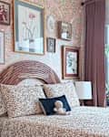 Cozy bedroom with floral wallpaper, a wooden headboard, decorative art, and a cat resting on the bed.
