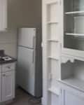 Modern kitchen with white cabinets, gray countertops, stainless steel sink, and a refrigerator.