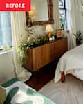 Cozy bedroom featuring a wooden bed, white bedding, a decorative mirror, and a side table with plants and a lamp.