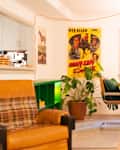 Cozy living space featuring a brown leather armchair, green shelving, a wooden dining table, and vintage movie poster decor.
