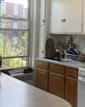 Bright kitchen with wooden cabinets, a window view of greenery, and a countertop with a fruit basket and dish rack.
