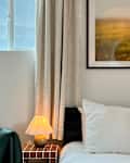 Cozy bedroom corner with a green sofa, white bedding, a green pillow, and a lamp on a side table.