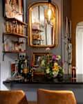 Cozy kitchen with dark cabinets, green tiled backsplash, a floral arrangement, and a bar area with glassware.