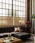 Cozy living room with a dark sectional sofa, a gold floor lamp, and a coffee table adorned with books and flowers.