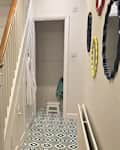 Graphic tile in hallway with white stairs before renovating.