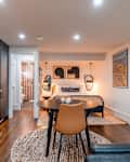Cozy studio apartment featuring a kitchen, dining table, bed with artwork, and a bathroom entrance.