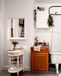 Cozy bathroom with a vintage tub, wooden sink cabinet, floral shower curtain, and a small round table with flowers.