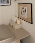 A corner with a framed portrait, a shelf with photos, a plush bunny, and a changing table with supplies.
