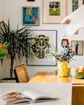 Dining area with a wooden table, yellow chairs, a floral centerpiece, and a gallery wall of framed art.