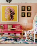 Eclectic living room with pink sofa, colorful rug, large plant, and vibrant artwork on a yellow background.