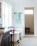 Bright bathroom with a clawfoot tub, colorful towel, wicker basket, and white cabinetry.