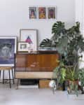 Mid-century cabinet with plants, framed art, and a turntable in a modern living room.