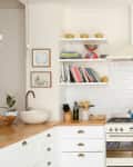 A simple white kitchen with open shelving instead of upper cabinets and butcher block counters