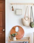 A round brown handbag is placed on top of a shoe rack, while two  handbags are hung on the wall making it a statement decor