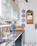 A galley kitchen with a stainless steel countertop and a stained glass window