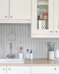White paneling behind white cabinetry in a kitchen