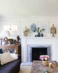 A living room with a white and blue ornate fireplace and a smaller TV in the corner