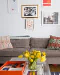 Gray sofa with patterned pillows, yellow tulips on a glass table, and framed art on the wall in a cozy living room.