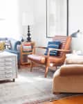 Cozy living room with a blue sofa, brown leather chair, beige armchair, and metal coffee table on a patterned rug.