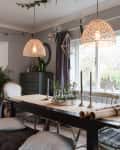 Dining room with a wooden table, pendant lights, Christmas tree, and star decorations by the window.
