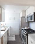A galley kitchen with white subway tile backsplash and gray quartz countertops
