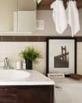Bathroom sink with a "No Bad Days" sign, soap, plant, and framed bridge photo on the counter.