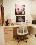 Home office with a white chair, desk, typewriter, laptop, wall art, and corkboard with photos and notes.