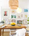 Dining room with wooden table, white chairs, sheepskin throws, lemon centerpiece, and eclectic wall art.