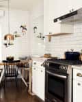A white kitchen with floor-to-ceiling subway tiles and a small round kitchen table