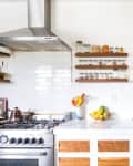 A white and wood farmhouse kitchen with pans hanging on hooks on the wall