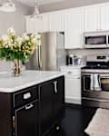 Modern kitchen featuring a marble-topped island, stainless steel appliances, and a vase of flowers.