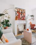 A white fireplace with an oversized piece of colorful artwork on top of the mantel