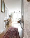 Open kitchen with patterned tile floor, white cabinets, open shelves, and a view into a bright living area with a red rug.