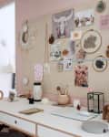 Home office with a white desk, mood board, decorative items, and a pink wall.