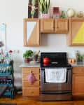 Kitchen with wooden cabinets, granite countertop, red kettle on stove, and decor items like plants and a globe.
