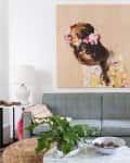 Gray sofa with colorful pillows, large floral artwork, white lamps, and a green plant on a round marble table.