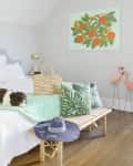 Bedroom with a polka dot headboard, dog on bed, tropical pillows, straw bag, and flamingo decor.