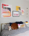 Bedroom with abstract art, polka dot bedding, plush pillows, and mirrored closet doors.