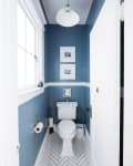 A white pendant light hangs above a small blue bathroom.