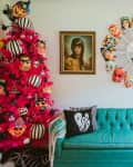 Teal sofa with ghost pillow, pink tree with masks, and framed portraits on wall with circular mirror.
