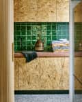 Kitchen with green tiled backsplash, wooden cabinets, black faucet, and folded towels on the counter.
